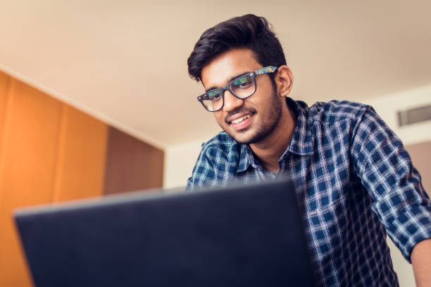 Video Conference, Youth, Technology, Communication - Young Man standing casually in front of his laptop and talking to the WebCam